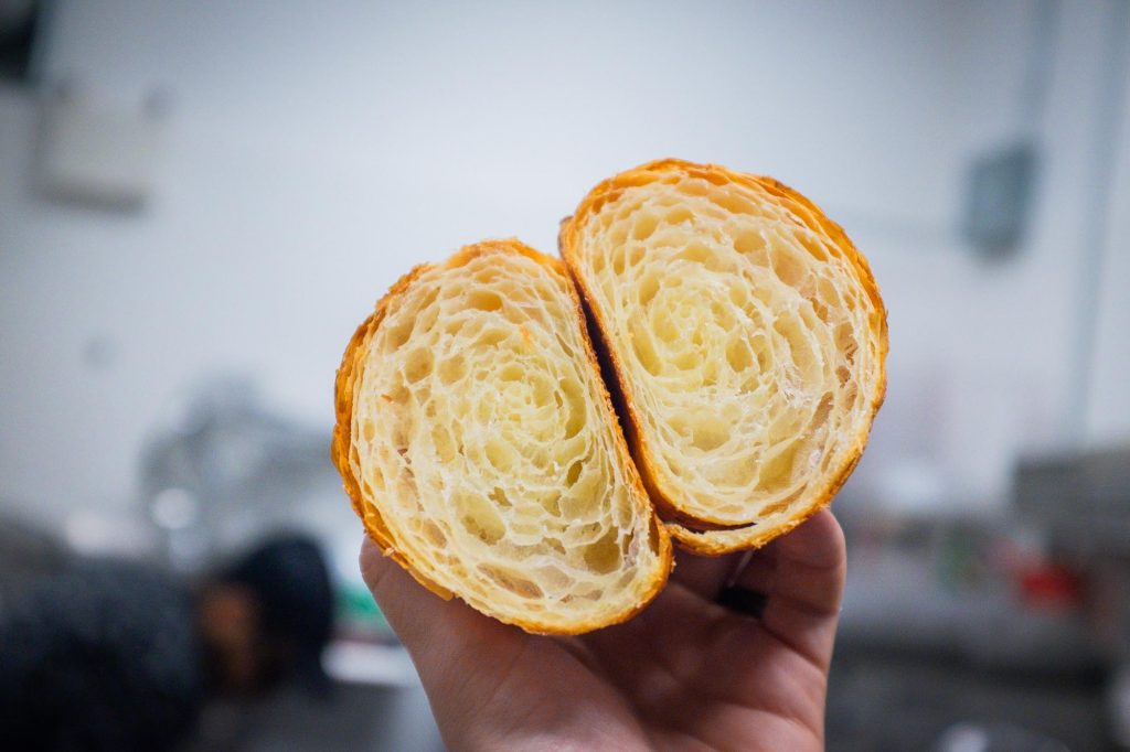 A croissant torn open to show its laminated layers