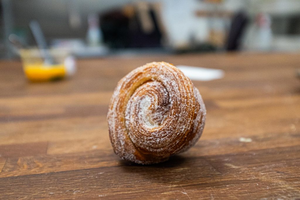 A sugared morning bun on a wooden bench